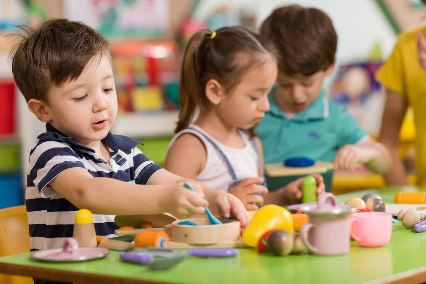 Young children playing with various toys on a table at a childcare center in the Newcastle area of NSW