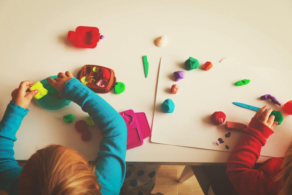 Young children playing with plasticine on a table at a childcare center in the Central Coast of NSW