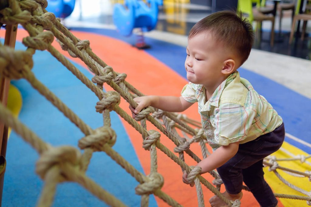 Young boy climbing up a cargo net at a childcare center in Campbelltown, Liverpool Sydney
